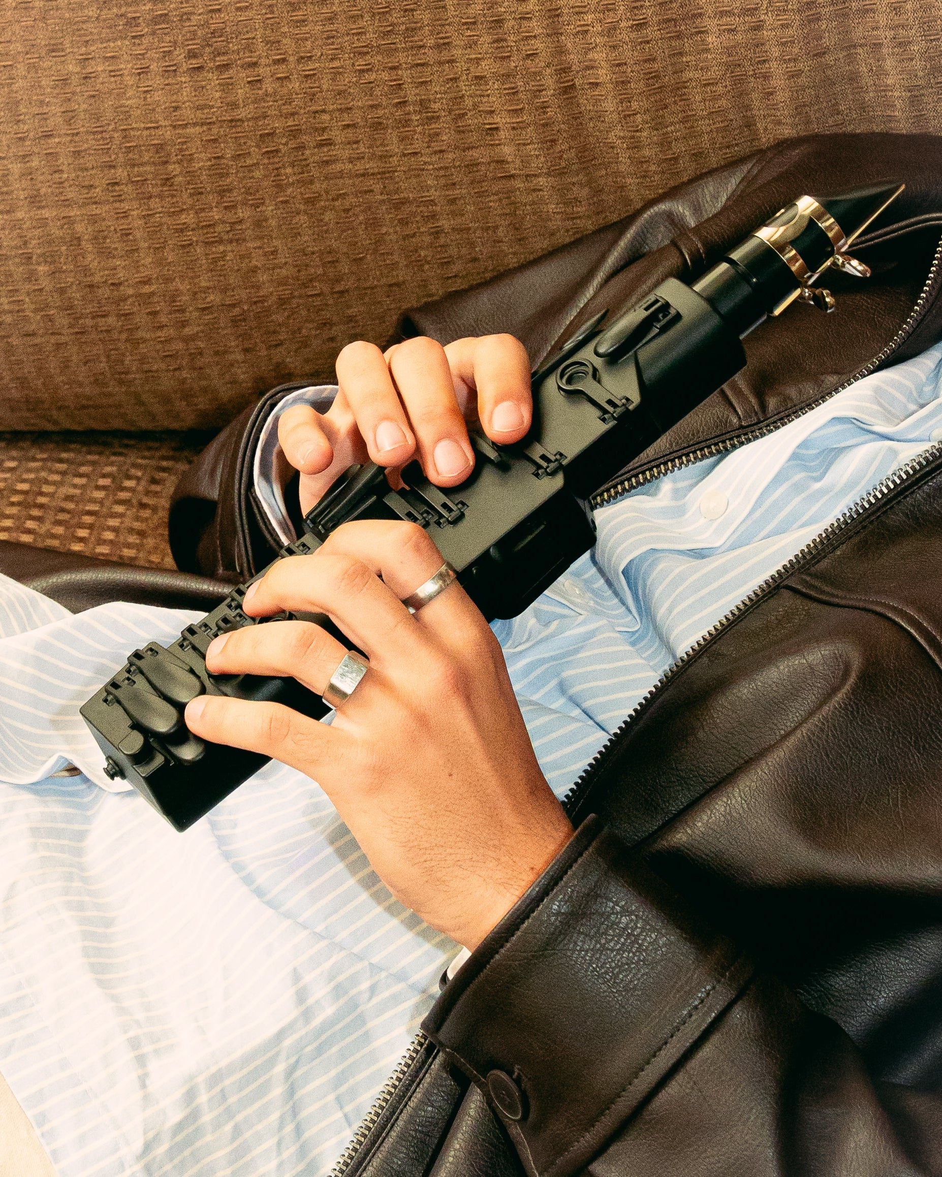 Person holding a black Trave Clarinet with a scope on a couch